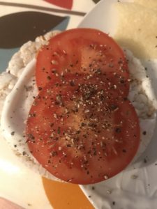 Simple snack of sliced tomato with ground black pepper and ricecake